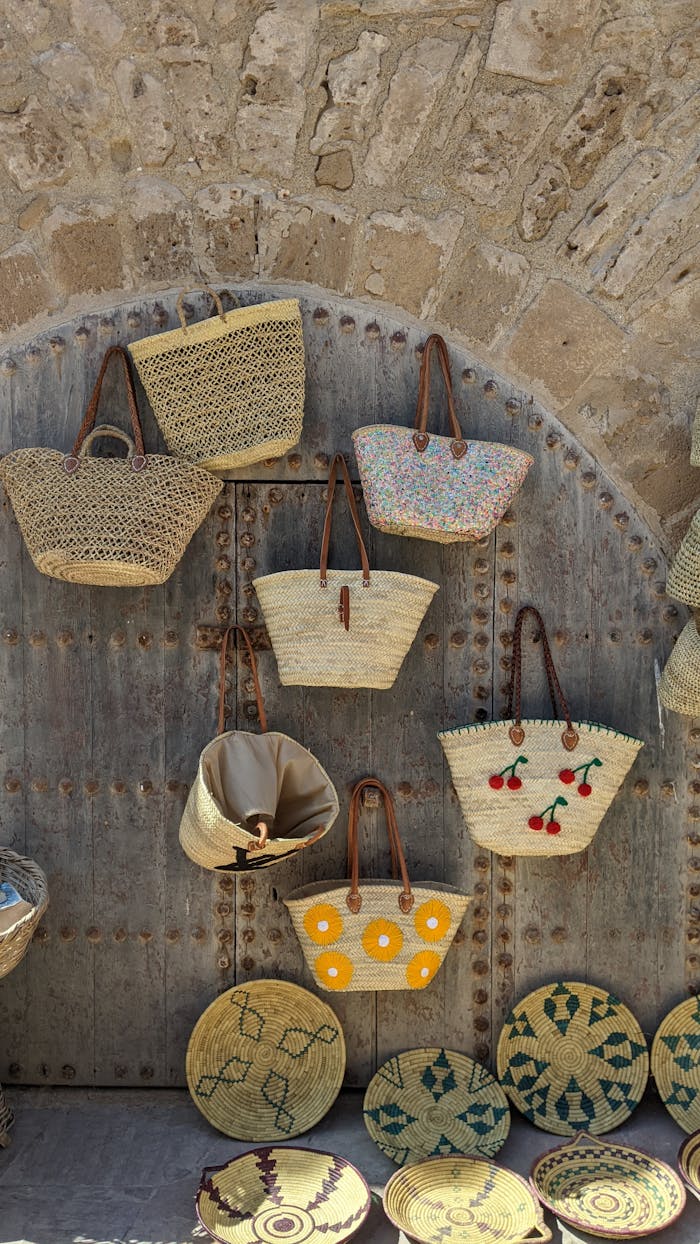 A display of handcrafted straw bags on a rustic stone wall in Essaouira, Morocco.